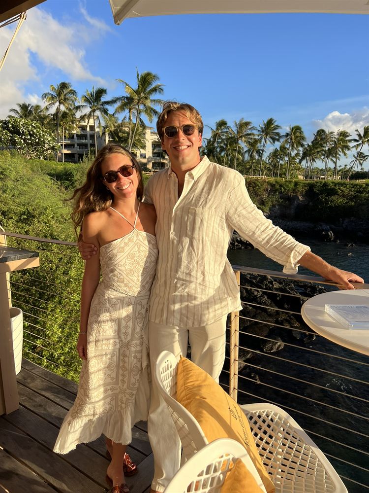 On a seaside balcony with palm trees behind them